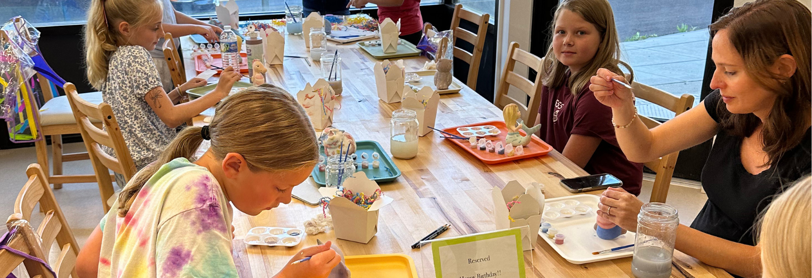 young artists painting during a paint your own pottery birthday party