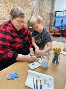 Family painting ceramic ornaments together during a holiday pottery activity at Pearl City Clay House, Jamestown, NY.