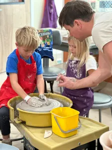 Family pottery class with kids and parent working together on the wheel at Pearl City Clay House in Jamestown, NY.