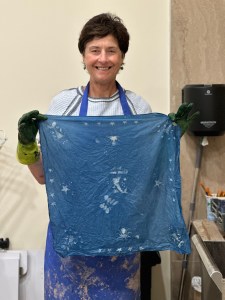 Student dipping fabric in indigo dye during a natural dyeing workshop at Pearl City Clay House, Jamestown, NY.