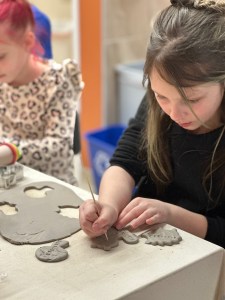 Young child creating a clay project by hand during a kids’ pottery class at Pearl City Clay House, Jamestown, NY.