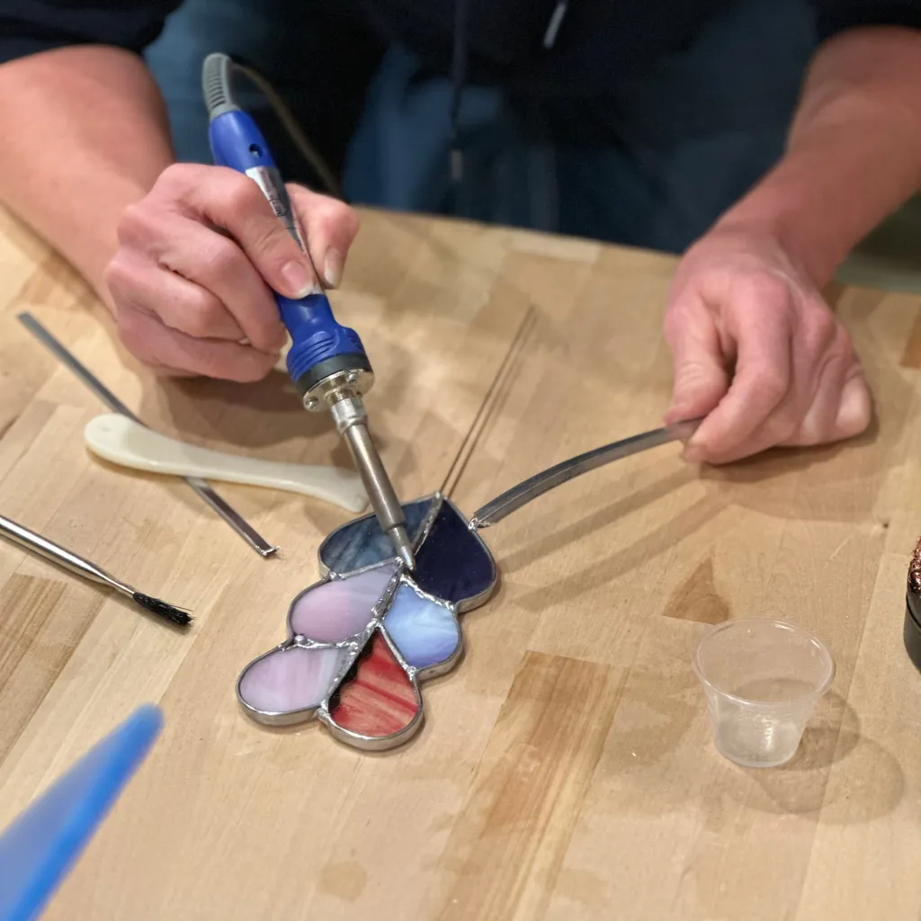 Close-up of a student assembling a stained glass project during a crafts workshop at Pearl City Clay House in Jamestown, NY