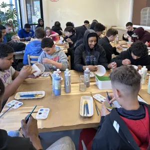 Students painting ceramic pieces in a group pottery session at Pearl City Clay House in Jamestown, NY